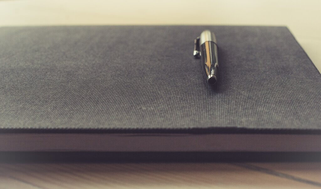 Notepad and pen for writing a meeting agenda